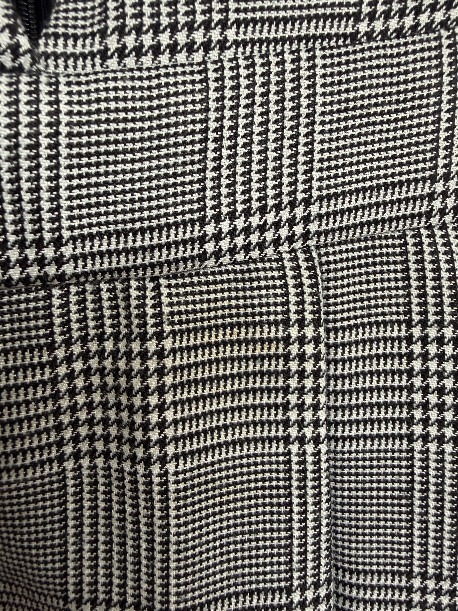 Close-up of a black and off-white houndstooth patterned fabric, showing the slight brown stain on the fabric.