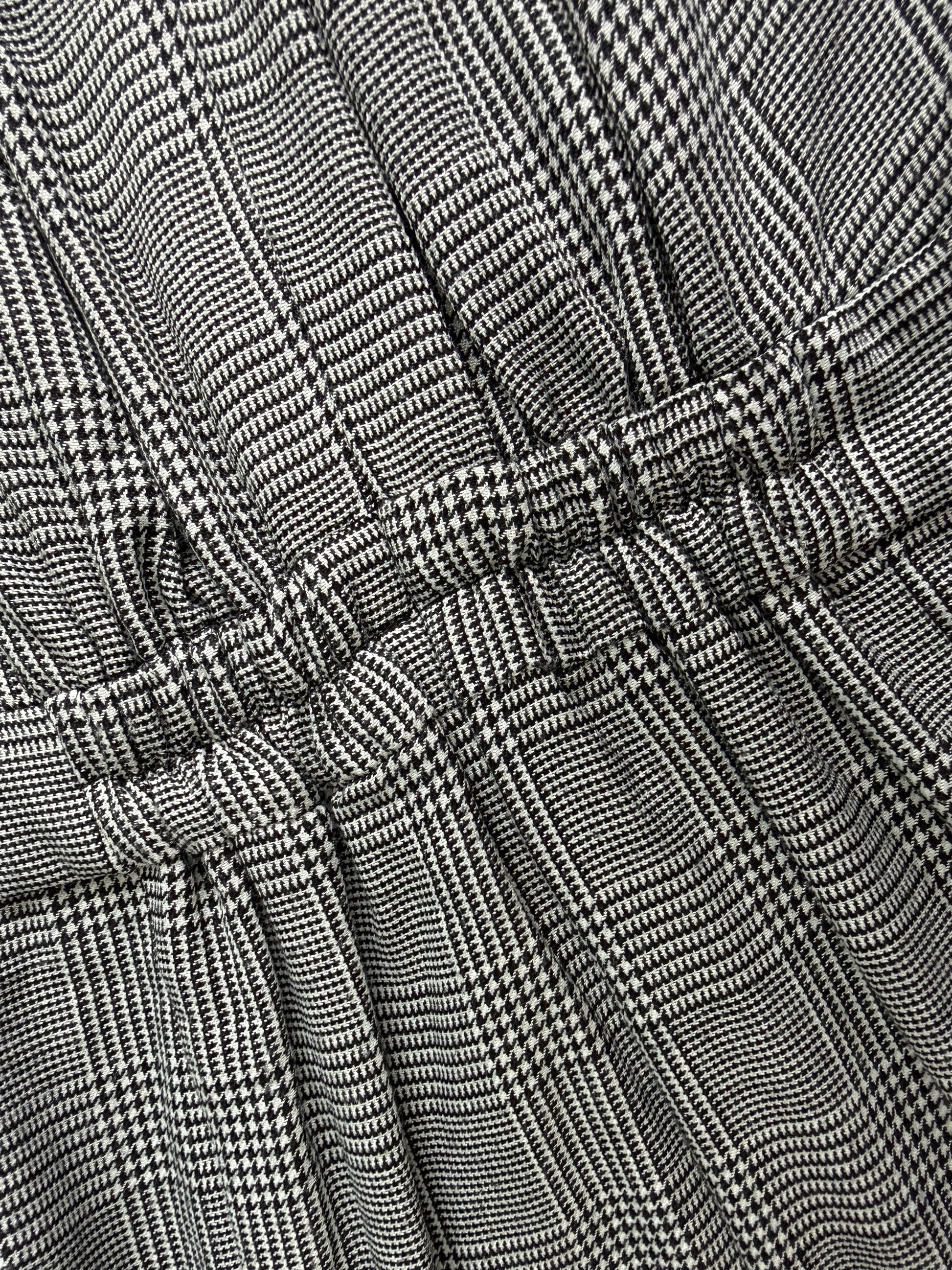 Close-up of a black and white micro-check patterned fabric with gathered pleats and a tie detail.