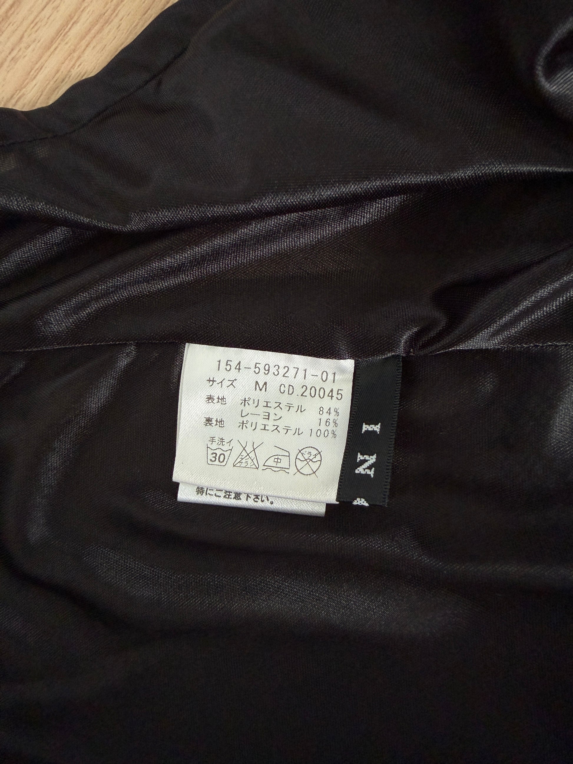 Close-up of a black satin or silk garment interior showing a sewn-in care label and brand tag on dark fabric.