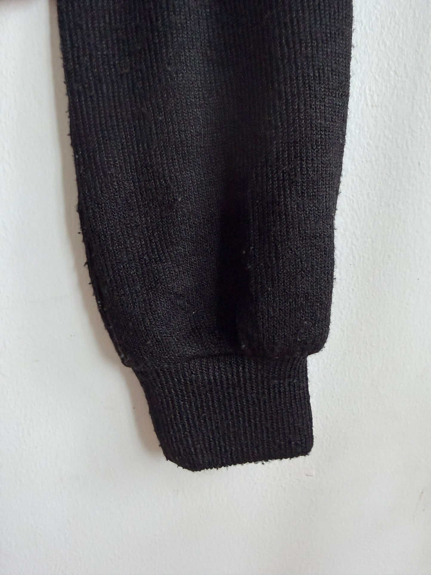 Close-up of a black ribbed knit sleeve or cuff against a plain white background.