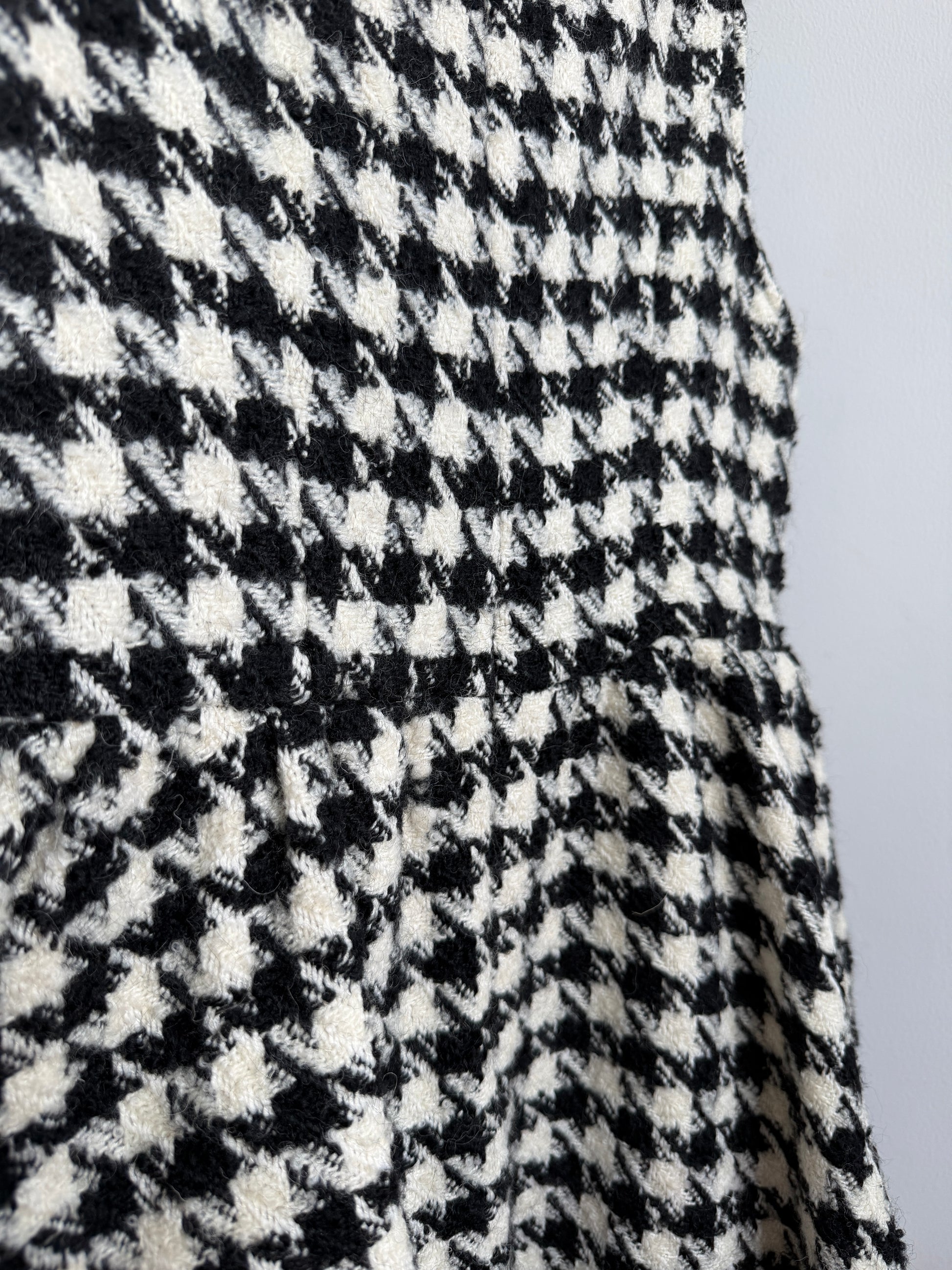 Close-up of a black and off-white houndstooth patterned fabric, showing the textured woven material and a gathered seam.