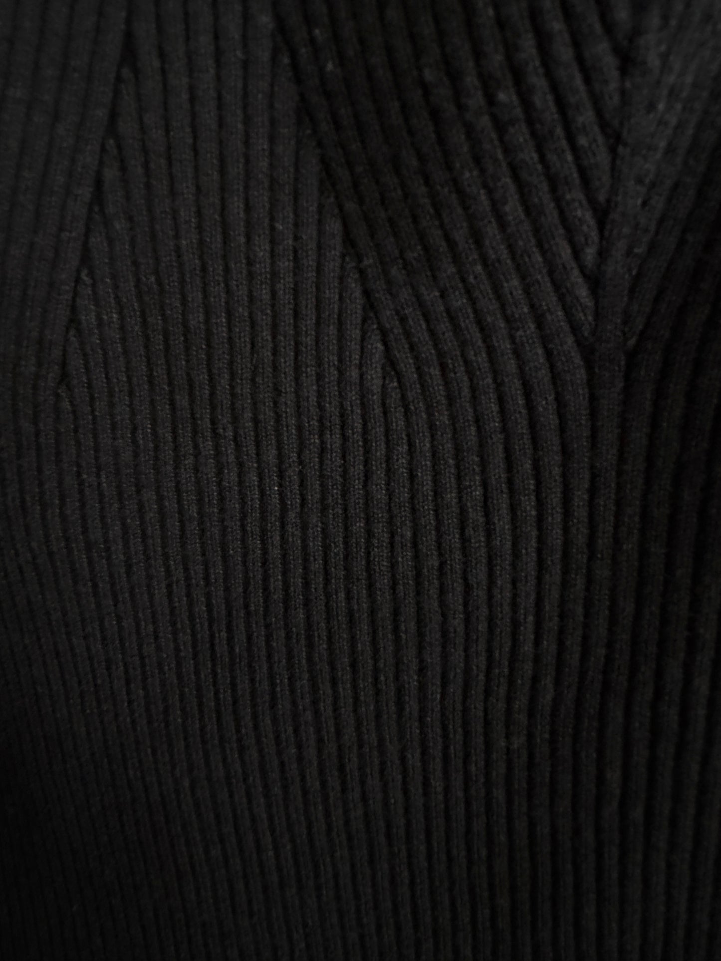 Close-up of a black ribbed knit fabric texture, showing the detailed vertical corduroy-like weave.