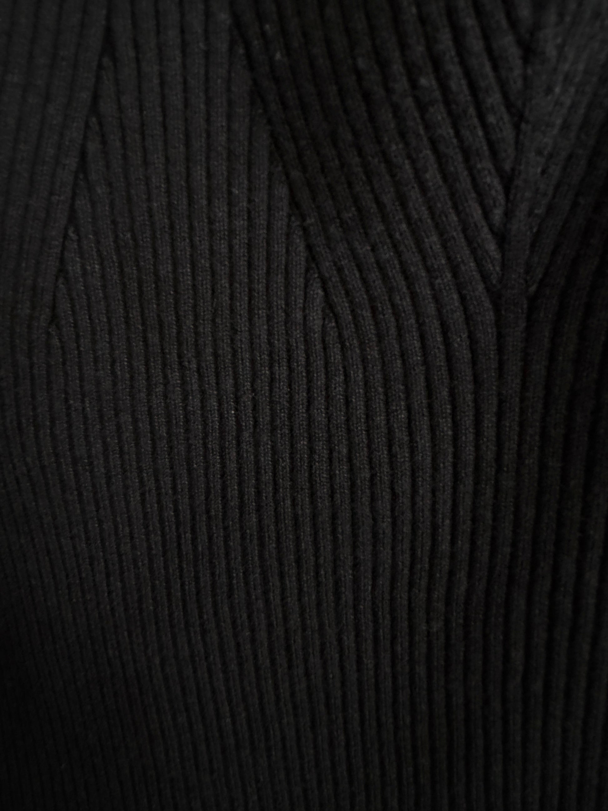 Close-up of a black ribbed knit fabric texture, showing the detailed vertical corduroy-like weave.