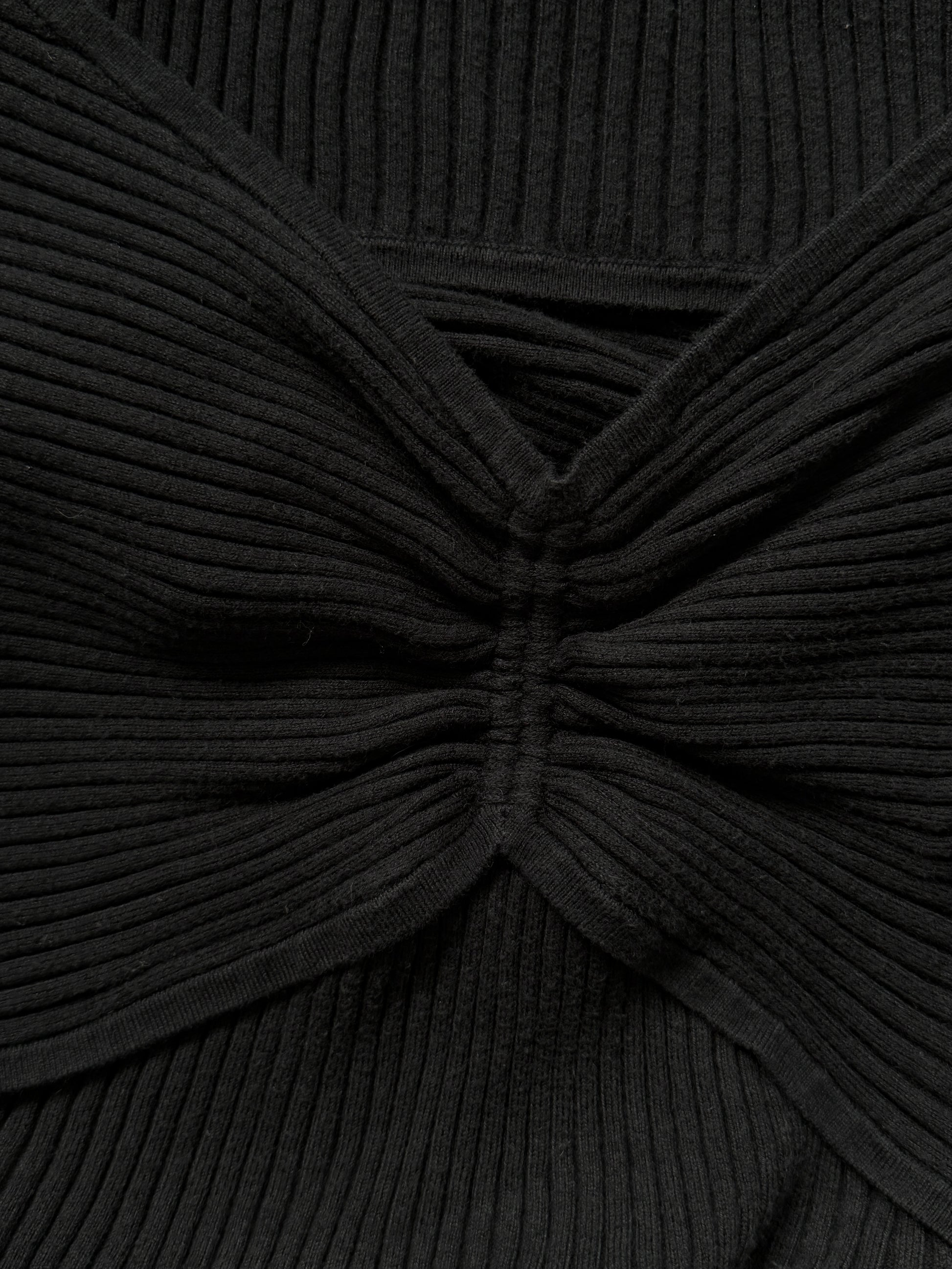 Close-up of a black ribbed knit top with a twisted knot or bow-like gathered detail at the center front.