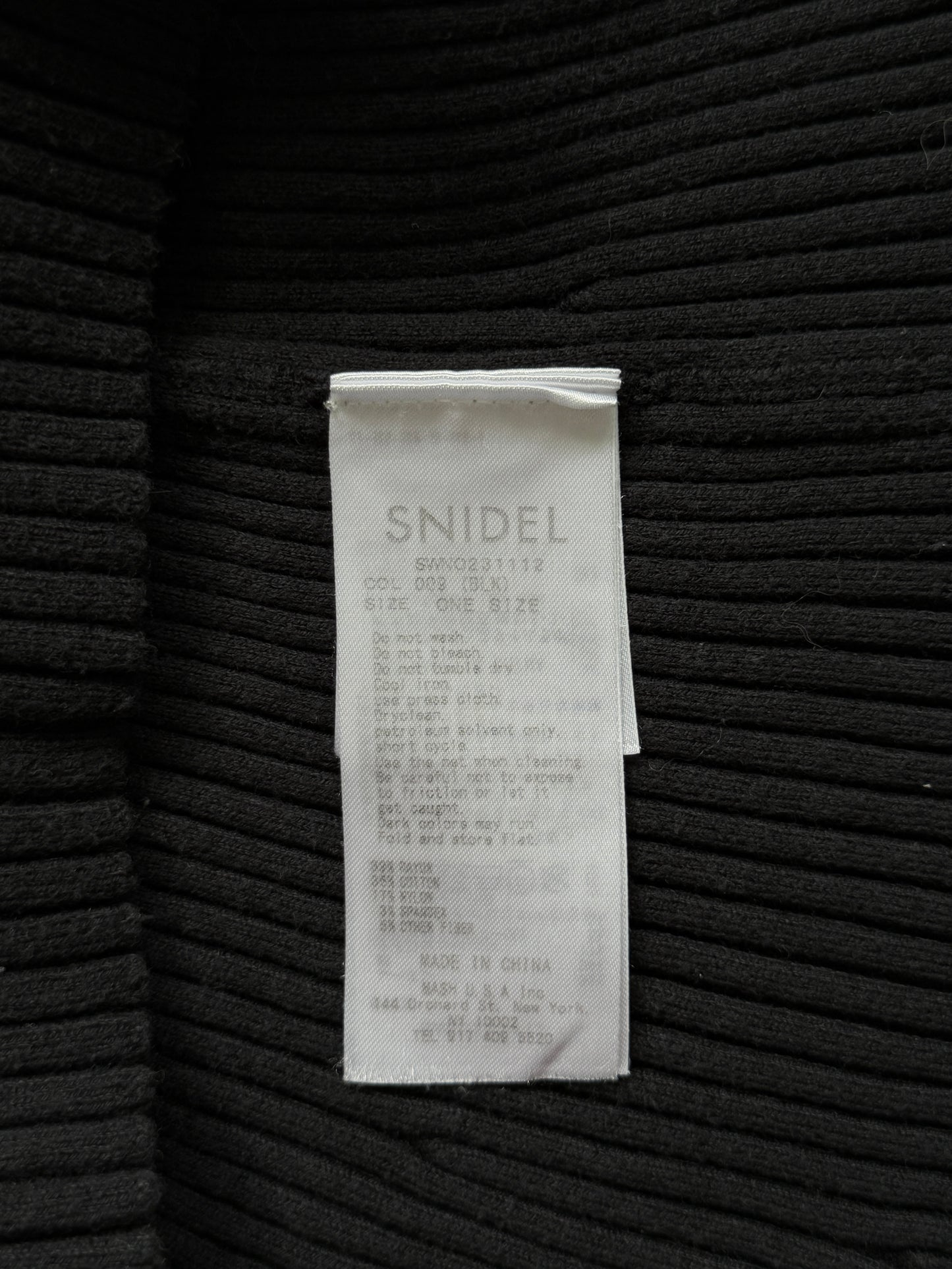 A close-up of a black ribbed knit garment showing a white paper size tag with the brand name 'SNIDEL' printed on it.