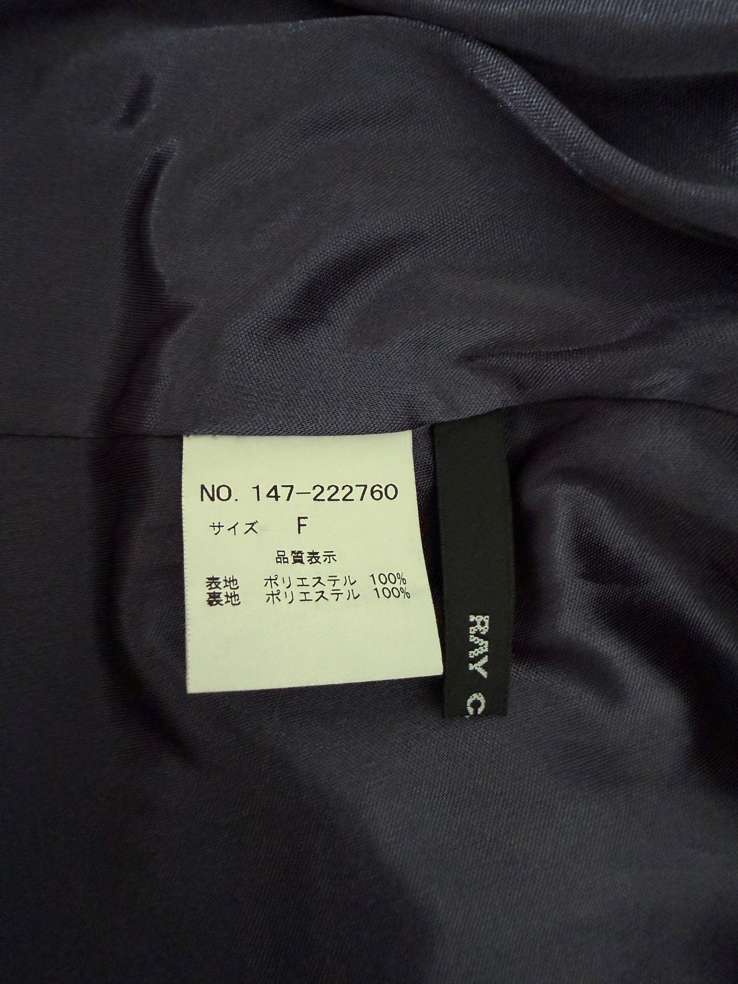 Close-up of a dark navy garment interior showing a white size label and a black Ray-Ban brand tag sewn onto the fabric.
