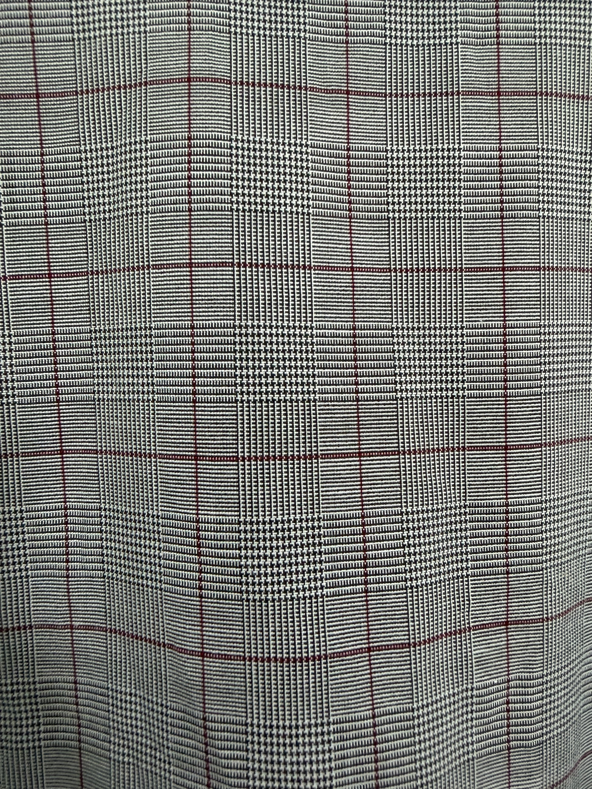 A close-up of a plaid fabric pattern featuring a black and white houndstooth weave with thin red windowpane lines.