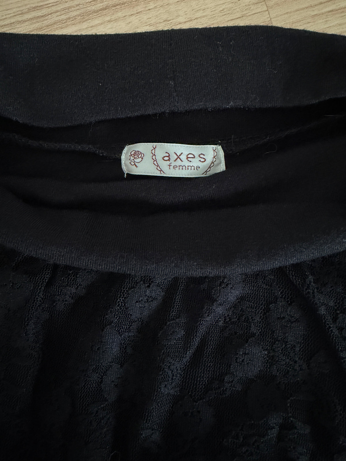 Close-up of a black lace garment with a visible neck label reading 'axes couture'.
