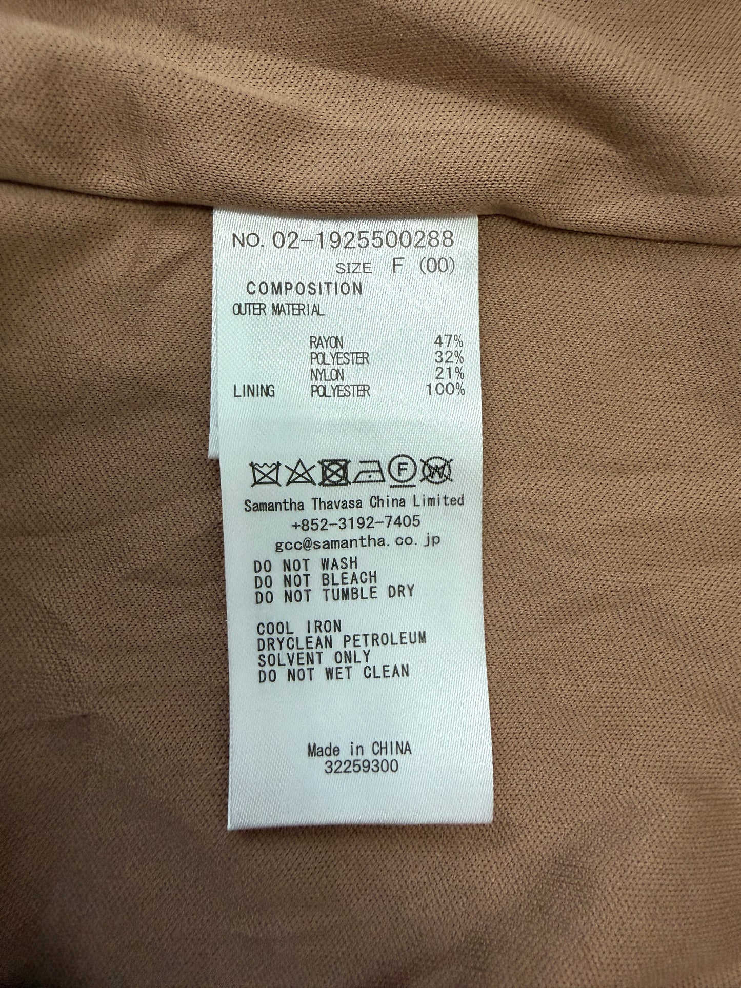 A close-up of a garment's interior label showing composition details, fabric percentages, care symbols, and manufacturer information for Samantha Thavasa China Limited.