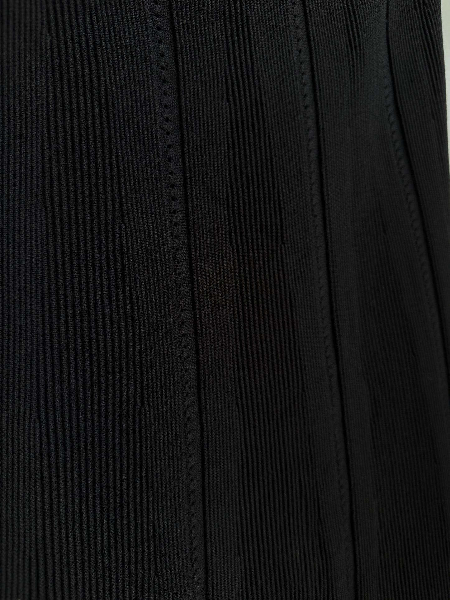 Close-up of a black ribbed fabric with vertical stitched paneling.
