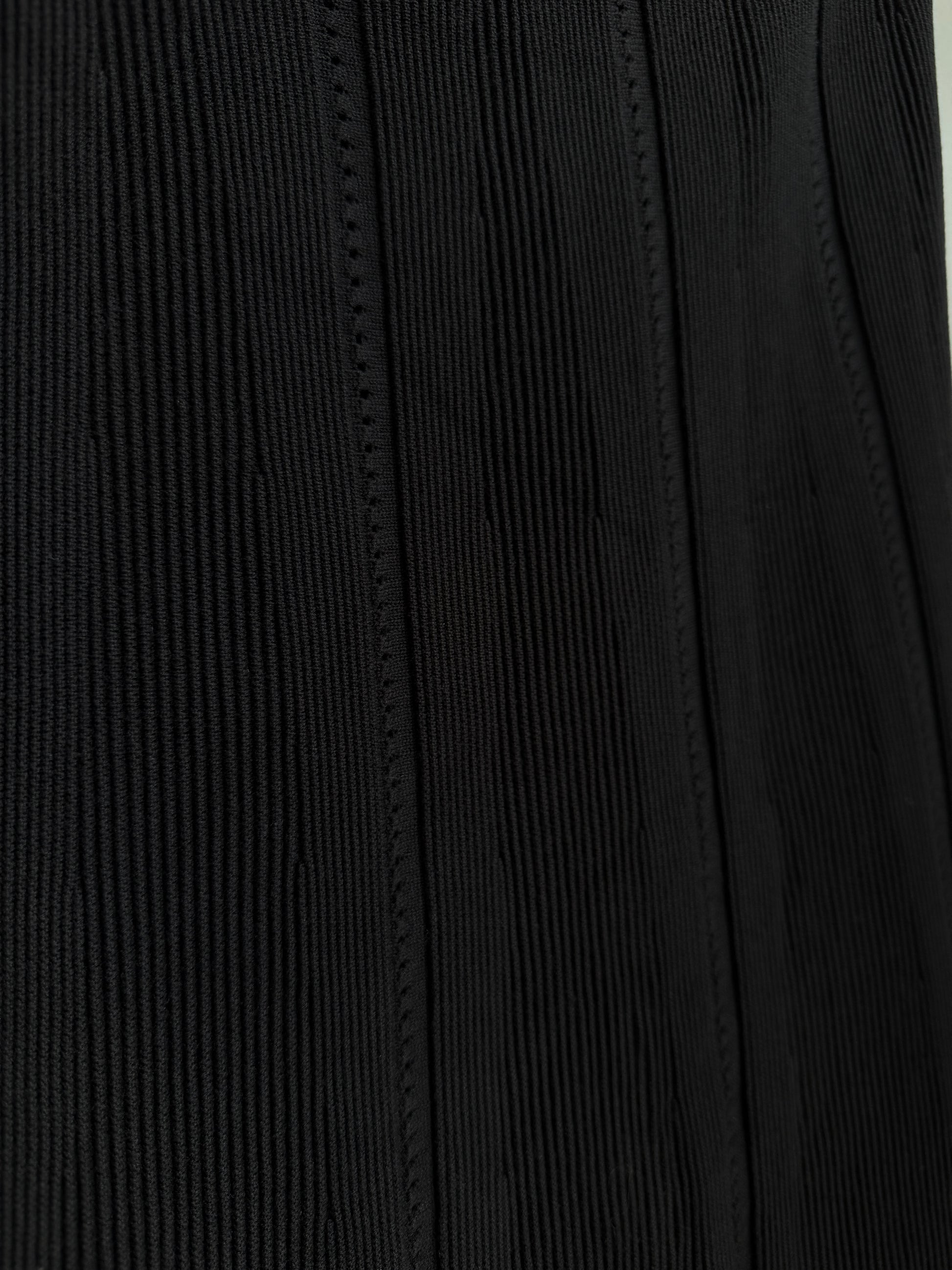 Close-up of a black ribbed fabric with vertical stitched paneling.