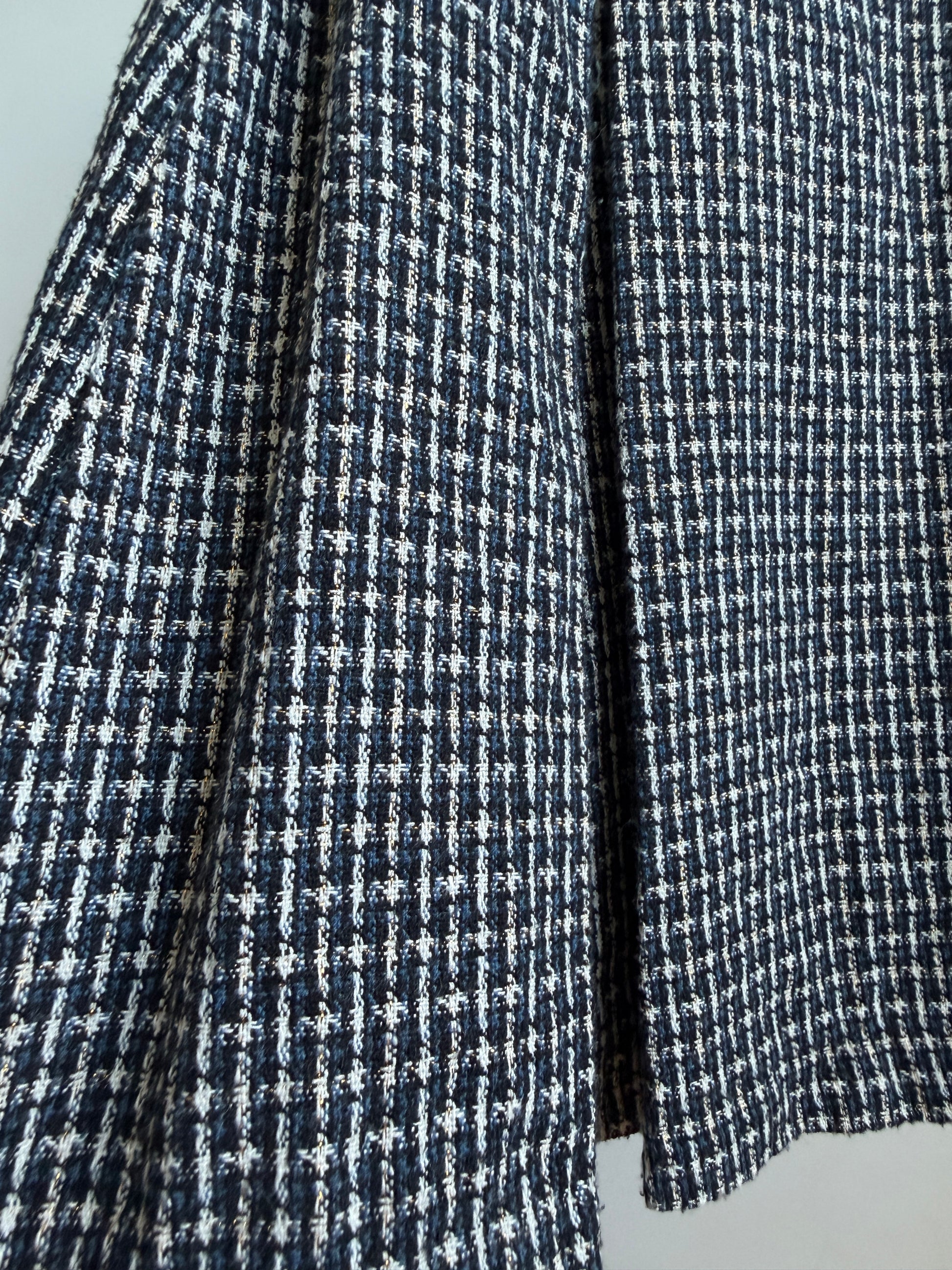 Close-up of a navy and white micro-check patterned fabric, likely tweed or woven wool, showing the texture and folds.